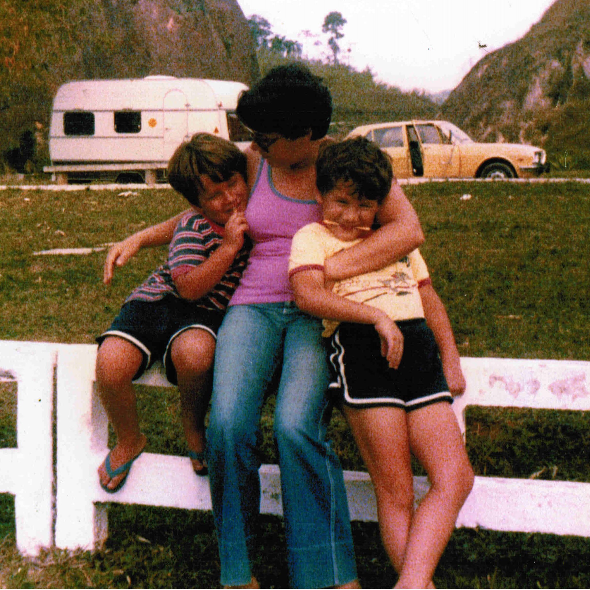Ana Maria Ribeiro Nogueira — known to everyone as Neneda — seated on a white wooden fence with her two young sons, Brazil, 1979.