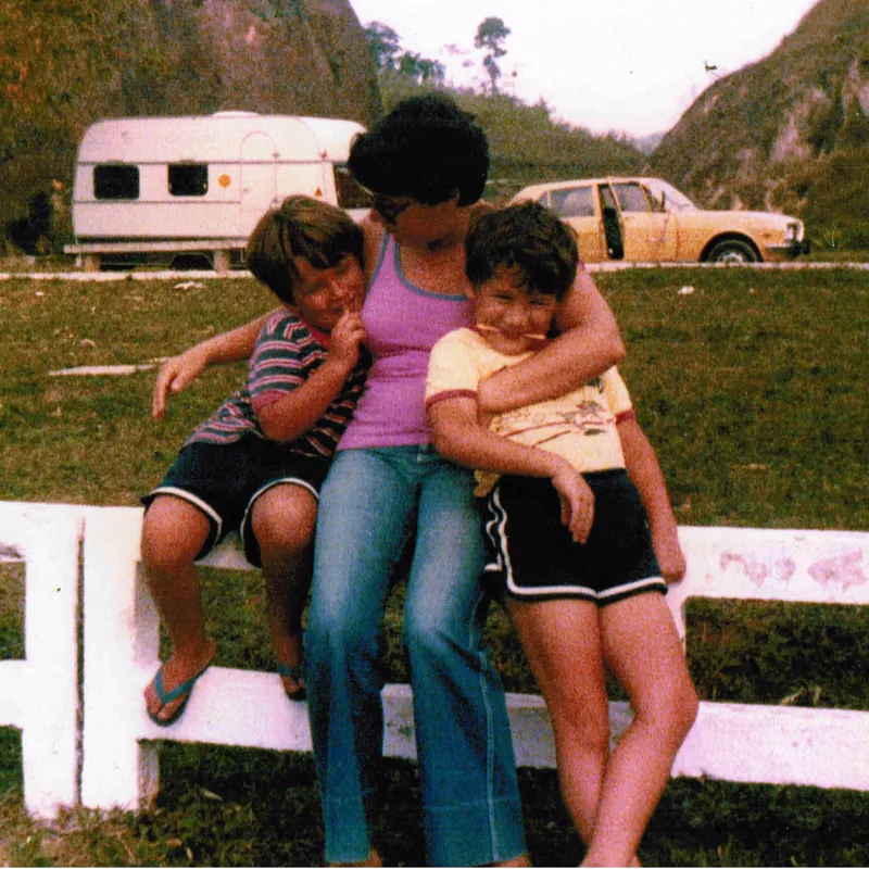 Ana Maria, known as Neneda, sits on a white fence with two young boys, in Brazil in 1979.