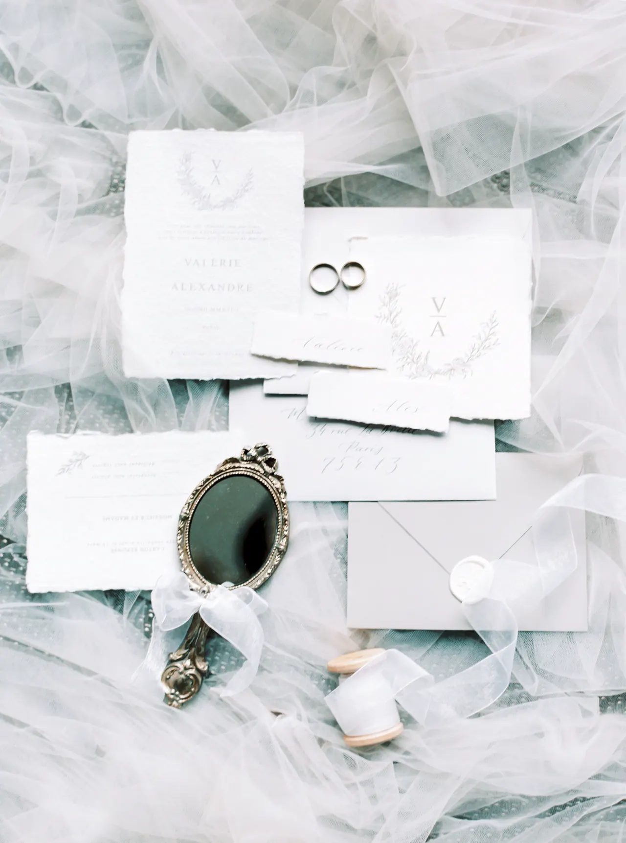 Wedding invitations and rings laid on soft tulle.
